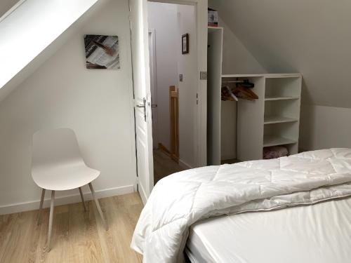 a bedroom with a white bed and a white chair at Gite Baie 3km plages in Telgruc-sur-Mer