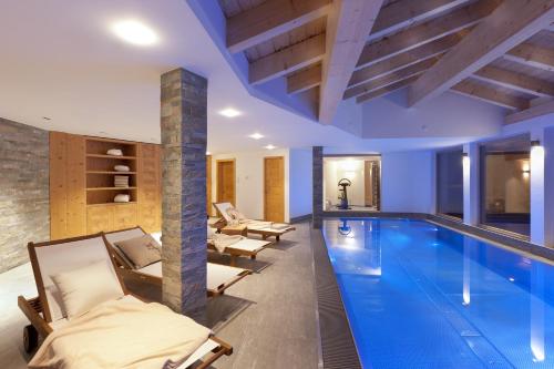 a swimming pool in a house with lounge chairs and a swimming pool at Chalet Banja in Zermatt