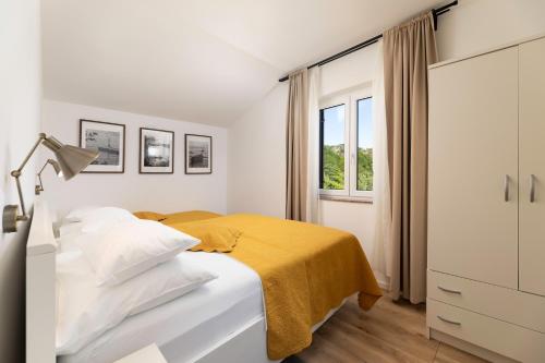 a white bedroom with a bed and a window at Apartments Maja in Baška