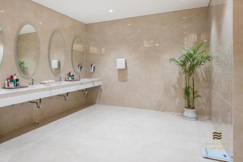 a bathroom with two sinks and two mirrors at Golden Sands Golf Resort in Hue