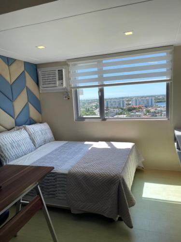 a bedroom with a bed and a large window at Comfy condo convenient location in Iloilo City