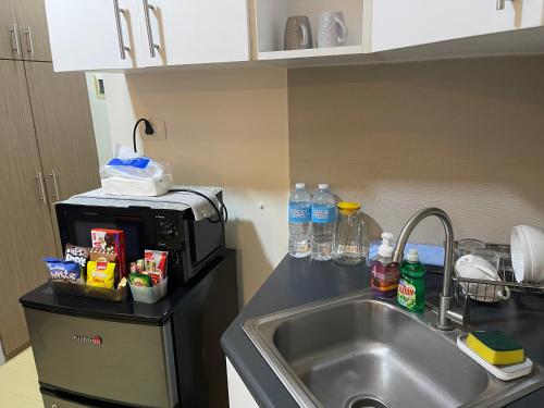 a kitchen counter with a sink and a microwave at Comfy condo convenient location in Iloilo City