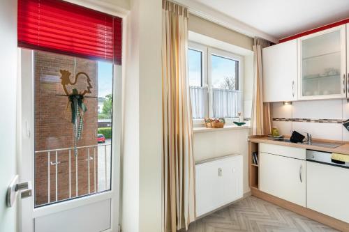 a kitchen with white cabinets and a large window at Südstadtquartier 108 in Wilhelmshaven