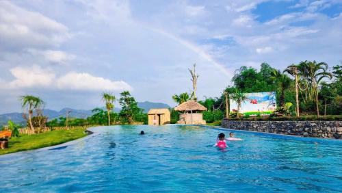 a child swimming in a pool with a rainbow in the background at Mây farmstay in Ðà Bắc