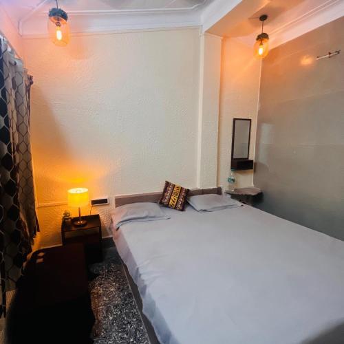 a bedroom with a large white bed with a lamp at Pebbles Guest House Digha in Digha