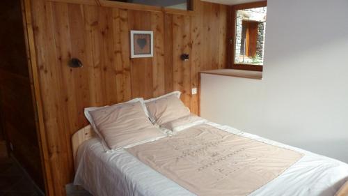 uma cama num quarto com uma parede de madeira em Mon petit Chalet em Valmeinier