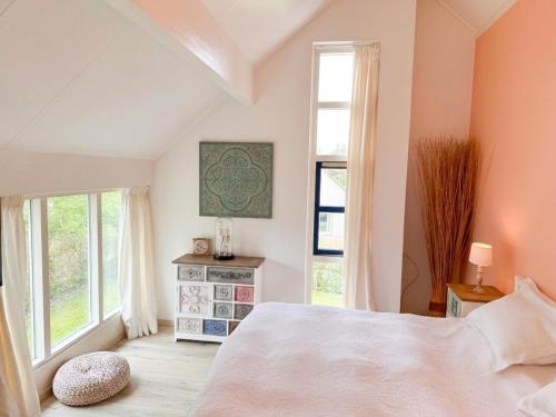 a bedroom with a large bed and a window at Villa Relax Ooghduyne - Dünen Golf und Spa bei Beach & more in Julianadorp
