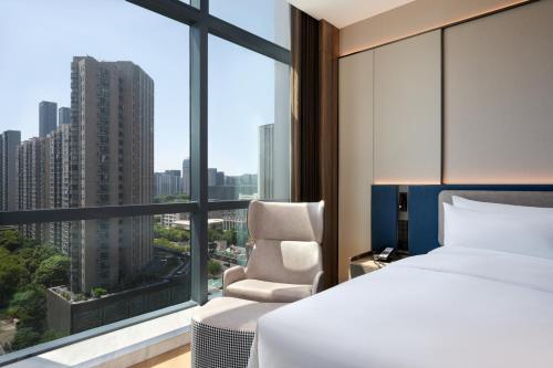 a bedroom with a bed and a chair and a window at Novotel Hangzhou Binjiang in Hangzhou