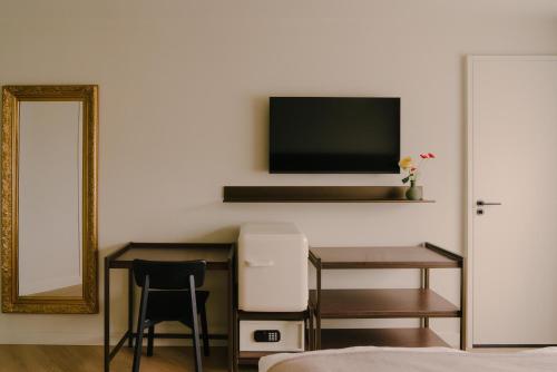 a bedroom with a desk and a television on a wall at Boutique Hotel Herbergh Amsterdam Airport FREE PARKING in Badhoevedorp