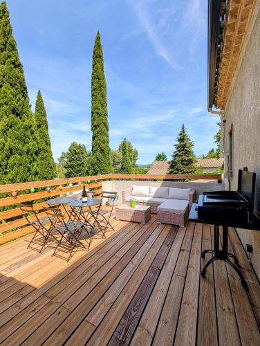 a wooden deck with a couch and a television on it at L'Ecrin de Pommayrac - Appartement Nature, au coeur d'un centre équestre in Verzeille