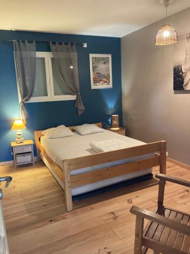 a bedroom with a bed with a blue wall at Villa ALoha in Carcans