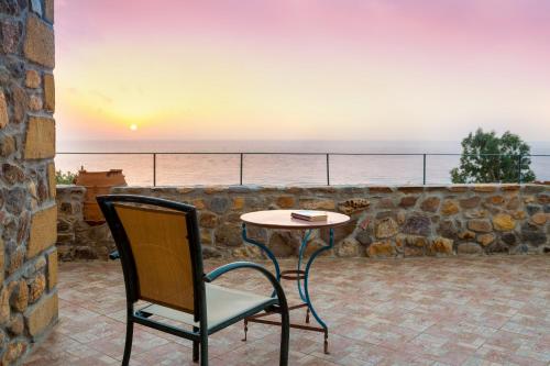 a table and a chair on a patio with the ocean at Villa Kimothoe with Private Pool, only 20 min to Elafonissi Beach in AmigdhalokeFálion