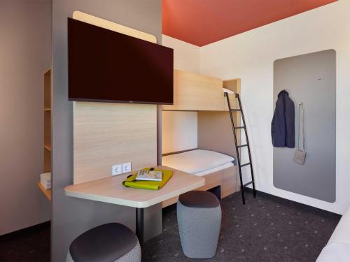 a small room with a desk and a bunk bed at B&B HOTEL Gütersloh in Gütersloh