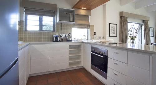 a kitchen with white cabinets and a stove top oven at Klein Welmoed Luxury Guest House in Stellenbosch
