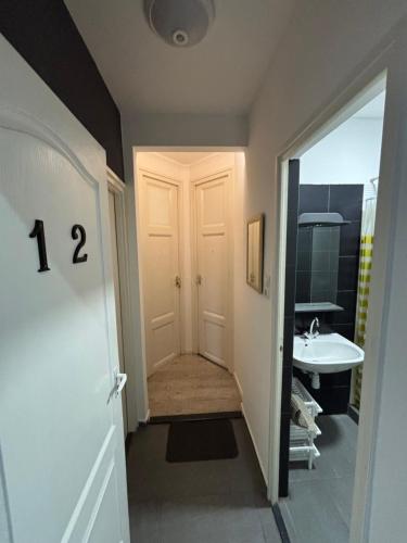 a hallway with a door leading to a bathroom with a sink at Centrum Vendégház in Debrecen
