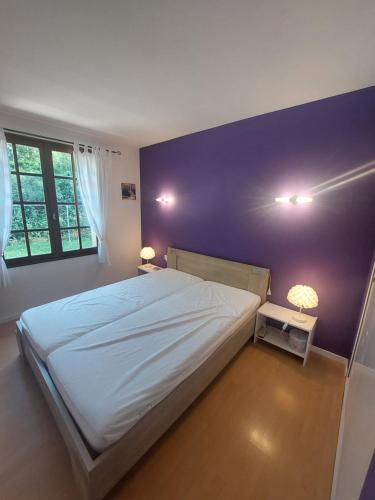 a bedroom with a large bed and a purple wall at Maison Lavande in Sousceyrac