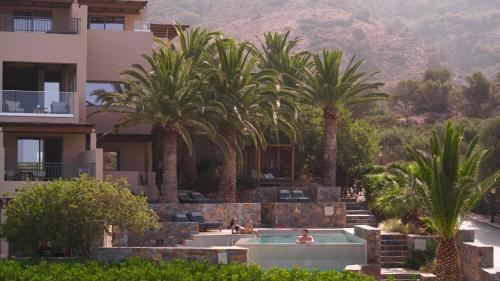 a resort with palm trees and a swimming pool at Paralos Irini Mare in Agia Galini