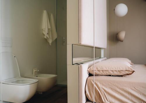 a bathroom with a bed and a toilet and a sink at Mafrica House in Aosta
