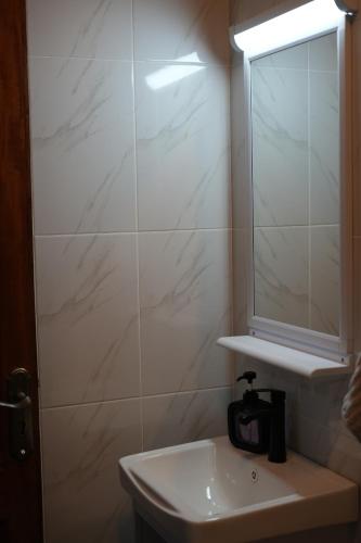 a white bathroom with a sink and a mirror at Elite Escape in Muchatha