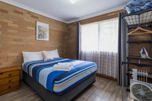 a bedroom with a bed and a brick wall at Emu Beach Chalets in Albany
