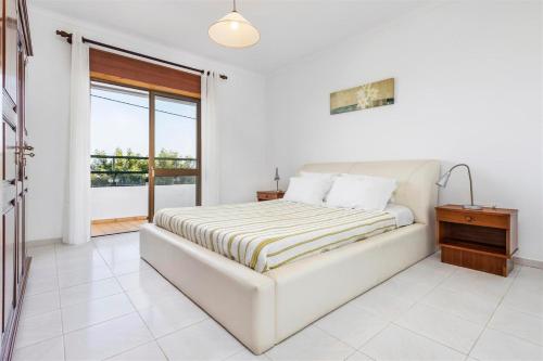 a white bedroom with a bed and a window at Casa Moura in Loulé
