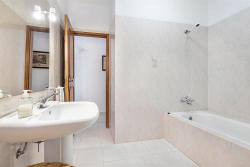 a white bathroom with a sink and a bath tub at Casa Moura in Loulé