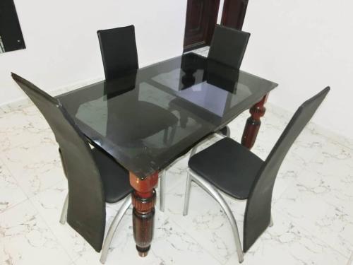 a glass dining table and two chairs on a marble floor at P M Serviced Apartments in Lagos