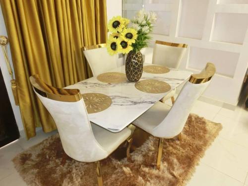 a table with white chairs and a vase of flowers at P M Serviced Apartments in Lagos
