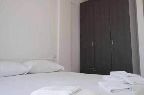 a bedroom with a bed with white sheets and a cabinet at Basilicata Host to Host - Le Muse in Stazione di Metaponto