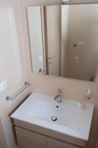 a bathroom with a white sink and a mirror at Basilicata Host to Host - Le Muse in Stazione di Metaponto