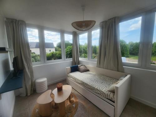 a living room with a couch and large windows at Le Carré Vert, appartement avec terrasse in Lamballe Armor