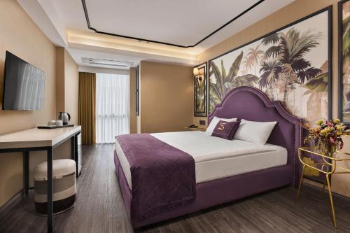 ein Hotelzimmer mit einem lila Bett und einem Schreibtisch in der Unterkunft The New Hotel Zeybek in Izmir