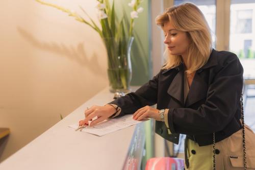 a woman standing at a counter writing on a paper at Villa Herkules - Adults Only in Świnoujście