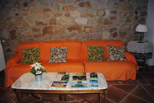 an orange couch in a living room with a table at Casa Rural Romanejo in Cabezabellosa