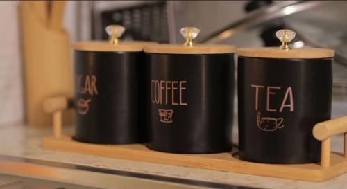 three black cups sitting on a wooden shelf at Atié Haven in Lira