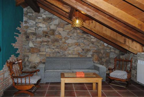 a living room with a couch and a stone wall at Casa Rural Romanejo in Cabezabellosa