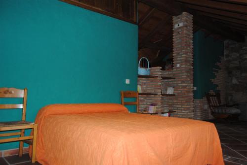 a bedroom with an orange bed and a blue wall at Casa Rural Romanejo in Cabezabellosa