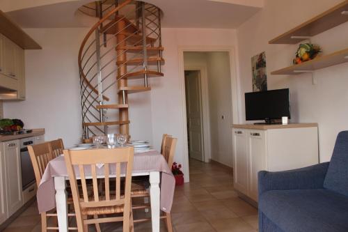 a kitchen and dining room with a table and a spiral staircase at Aba Village RTA in Puntone di Scarlino