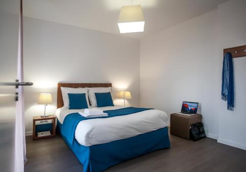 um quarto com uma cama com lençóis azuis e brancos em Odalys City Metz Manufacture em Metz