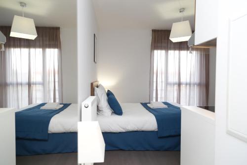 a bedroom with two beds and two windows at Appart Hotel Odalys City Metz Manufacture in Metz