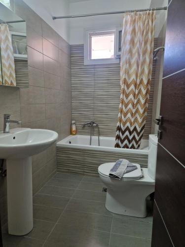 a bathroom with a sink and a toilet and a tub at Harry's Apartment in Lefkimmi