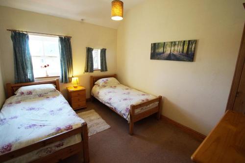 a small bedroom with two beds and a window at Y Stablau - The Stables in St. Davids