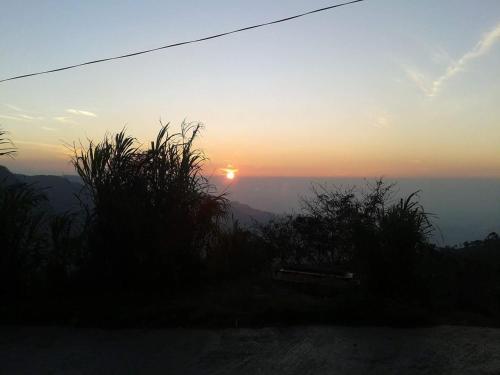 a sunset with the sun setting in the distance at Bel View Guest House in Haputale