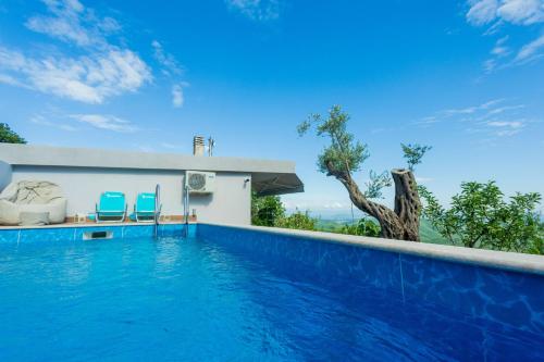 a swimming pool with two blue chairs and a house at Nature Oasis Kravari - Private Pool & Jacuzzi in Stegvaši