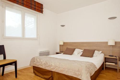 una camera con un grande letto e una finestra di Residhome Genève Prévessin Le Carré d'Or a Prévessin-Moëns