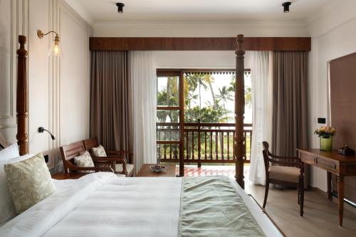 a bedroom with a bed and a desk and a window at Sanskreti in Cochin