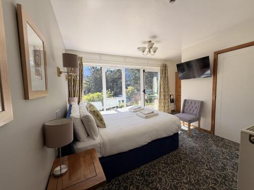 a hotel room with a bed and a window at Loch Leven Hotel & Distillery in Glencoe