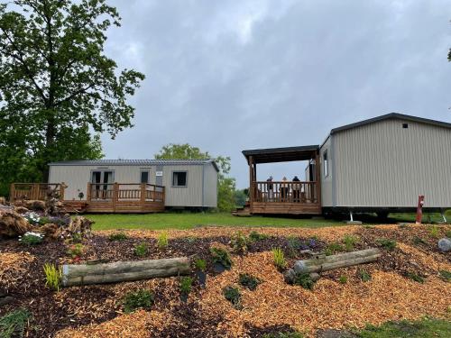 two mobile homes in a yard with trees at Siblu Prϋβsee in Güster