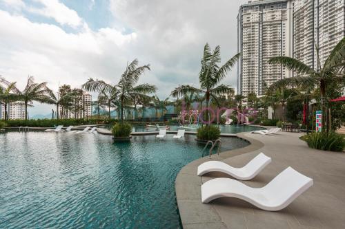 a swimming pool with white chairs and buildings at Antharas 1 Premier Suites Genting Highlands in Genting Highlands