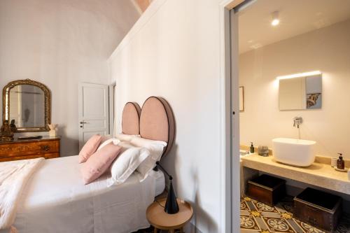 a bedroom with a bed with pink pillows and a sink at Palazzo Saetta in Nardò